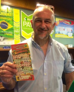 un sorridente Roberto Riva mostra la schedina vincente giocata nel suo locale pubblico 